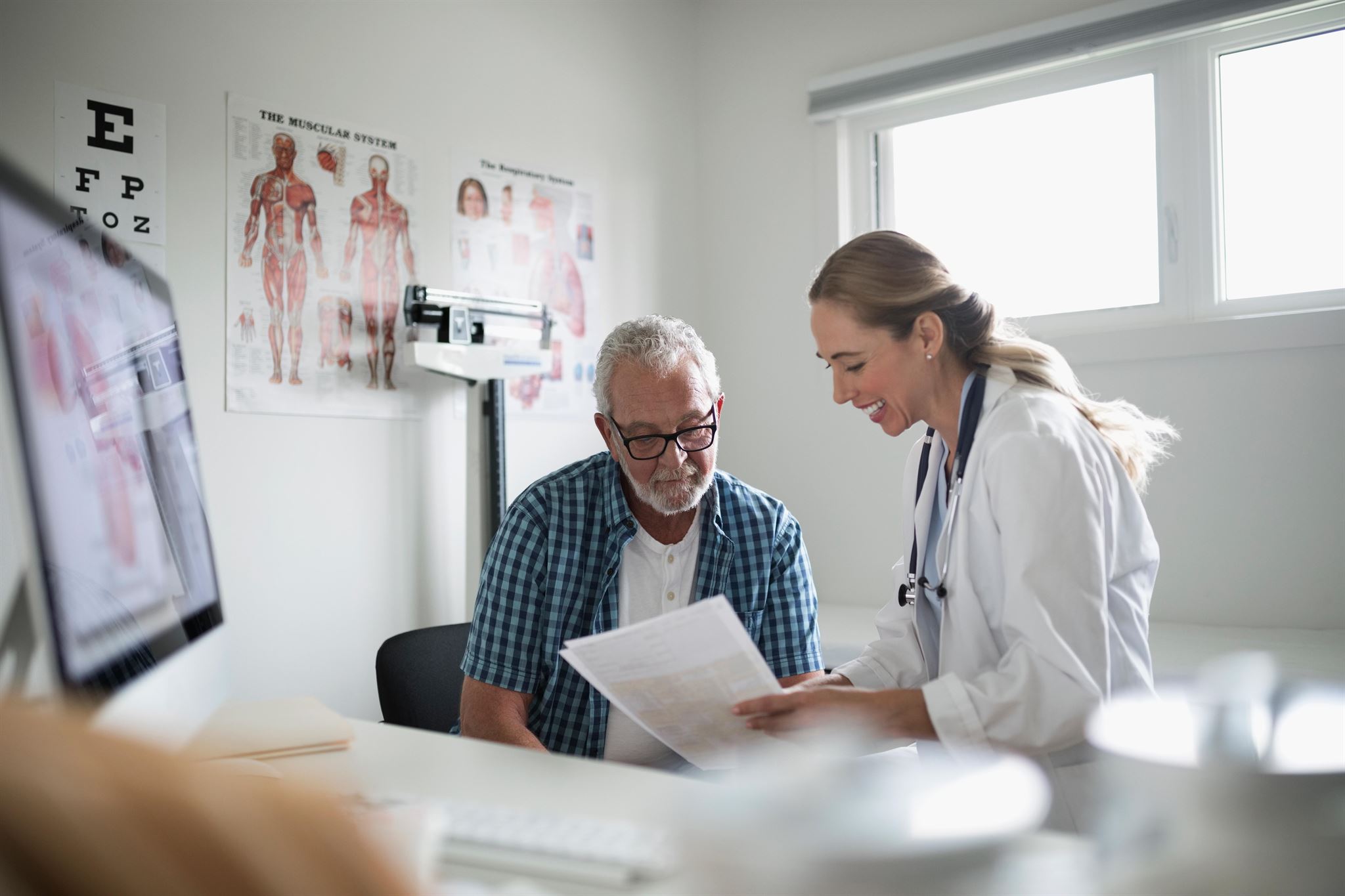 Doctor-explaining-paperwork-to-a-patient-in-an-examination-room